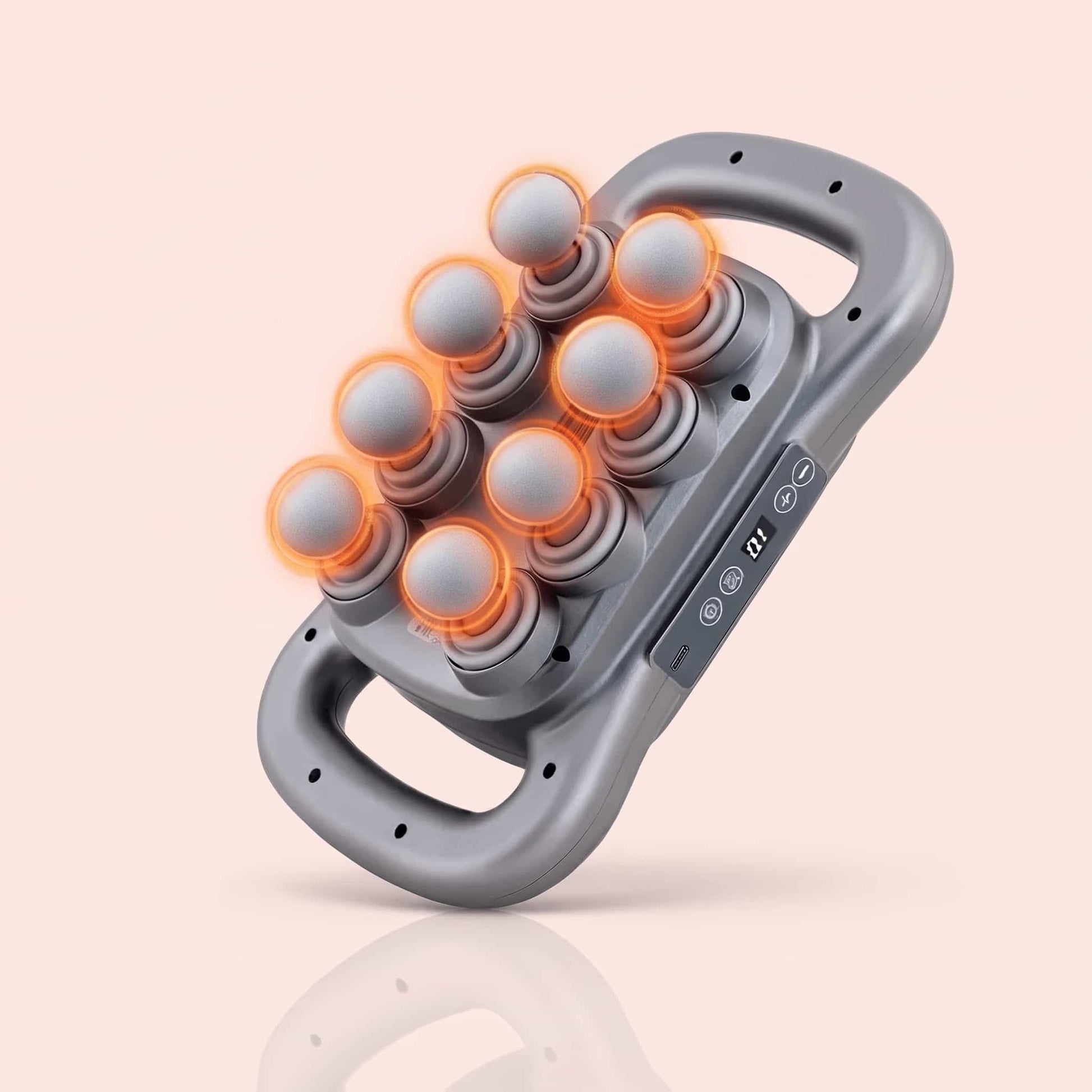 A gray handheld massage device with multiple rounded massage nodes illuminated by orange LED rings, shown on a soft peach background with a faint reflection below.